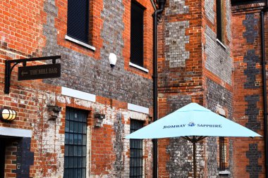 Whitchurch, Hampshire, İngiltere - Ağustos 2021: Bombay Sapphire Gin Damıtımevi 'nin bir kısmını oluşturan eski tarihi binalardan birinin önündeki güneş şemsiyesi