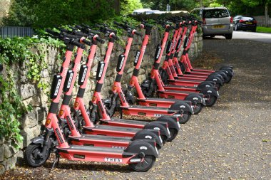 Bath, İngiltere - Ağustos 2021: Şehirdeki bir scooter paylaşım sisteminin bir parçası olarak üst üste kiralık olarak park edilen elektronik e-scooterlar