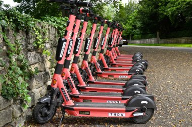 Bath, İngiltere - Ağustos 2021: Şehirdeki bir scooter paylaşım sisteminin bir parçası olarak üst üste kiralık olarak park edilen elektronik e-scooterlar