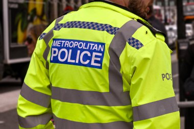 Londra, İngiltere - Ağustos 2021: Yansıtıcı ceket giyen bir Metropolitan Polisi 'nin arka görüntüsü. Arka planda kalabalıklar var..