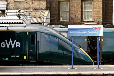 Londra, İngiltere - Ağustos 2021: Londra Paddington tren istasyonundaki platformlardan birine imza atın. Arka planda Büyük Batı Demiryolu 'nun yüksek hızlı treni var..