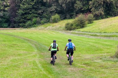 Stroud, İngiltere - Ağustos 2021: Dağ bisikletli iki kişi kırsal bir alanda bisiklet sürüyor