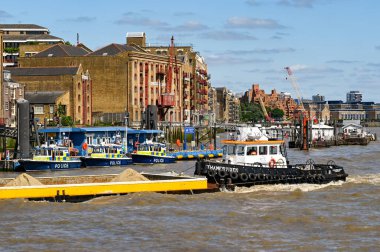Londra, İngiltere - Ağustos 2021: Thames Nehri üzerindeki bir köprünün altından geçen sanayi mavnası.