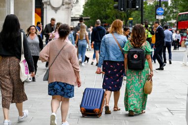 Londra, İngiltere - Ağustos 2021: Londra şehir merkezindeki Oxford Caddesi 'nde tekerlekli bavul çeken kişi