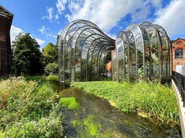 Whitchurch, Basingstoke, Hampshire, İngiltere - Ağustos 2021: Laverstoke Mill 'de iki büyük cam ev, Bombay Sapphire cininin imalathanesi. Önplanda nehir testi var..