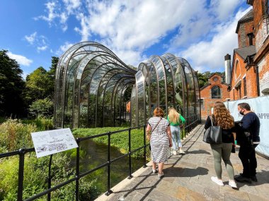 Whitchurch, Basingstoke, Hampshire, İngiltere - Ağustos 2021: Laverstoke Mill 'de iki büyük cam ev, Bombay Sapphire cininin imalathanesi. Önplanda nehir testi var..