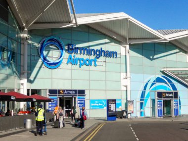 Birmingham, İngiltere - Eylül 2021: Birmingham Uluslararası Havaalanı 'ndaki terminal binasının önünde bavulları çeken insanlar