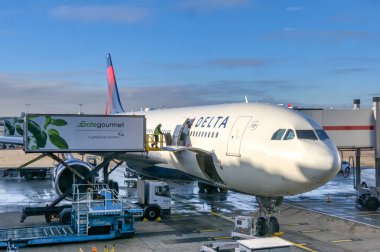 Londra, İngiltere, İngiltere - 11 Ocak 2024: Gategourmet Havayolları yemek ve içecekleri Delta Air Lines tarafından işletilen bir jete yükleyen kişi