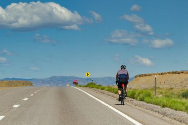 Moab, Utah, ABD - 26 Mayıs 2025: Utah 'ta büyük bir yol boyunca bisiklet süren kişi