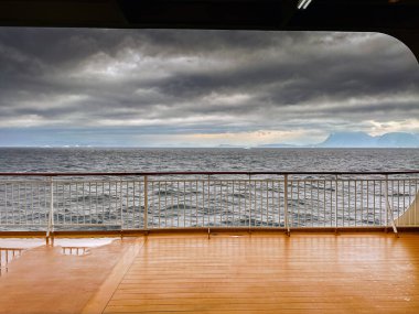 Atlantik Okyanusu, Grönland - 28 Ağustos 2024: Dalgalı bir deniz ve Grönland kıyıları olan bir yolcu gemisinin boş güvertesi.