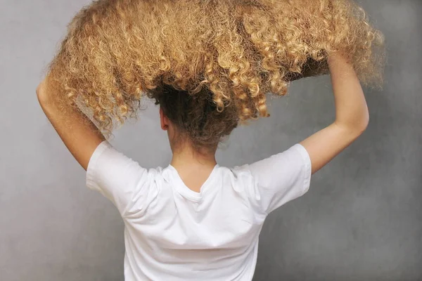 少女は太くて波状の髪を持ち上げる 後ろの景色 ヘアケアの概念 美容アートのアイデア — ストック写真