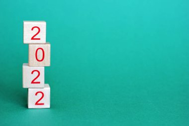 2022 sayıları, yeşil arka planda bir piramidin içinde üst üste duran tahta blokların üzerindedir. Yeni yıl 2022 konsepti. Mutlu yıllar..