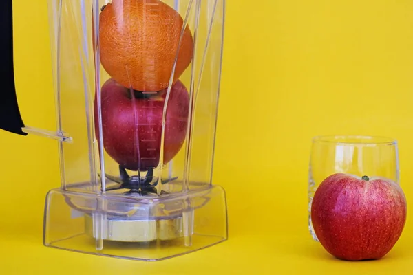 Friska livsmedel. Vitaminmat. Frukt i en mixer på en gul bakgrund. äpple och apelsin — Stockfoto