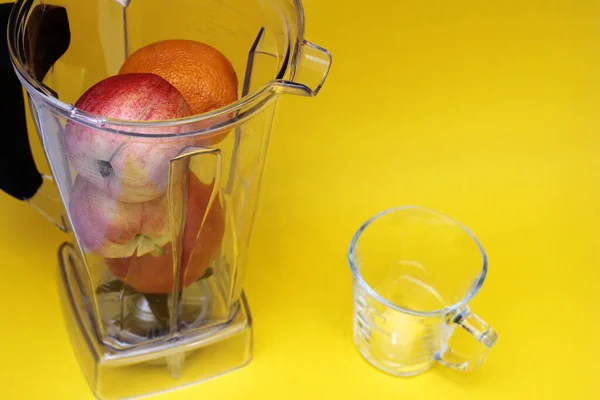 健康食品。维生素食品。在黄色背景下的搅拌机中的水果。苹果和橙子 — 图库照片