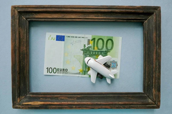 这款玩具飞机座落在100欧元的欧元钞票上，底部是蓝色的老式木制框架. — 图库照片
