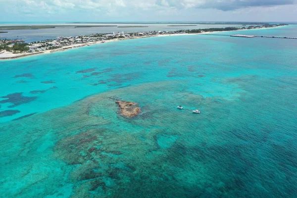 Mercan kayalarından demir atmış teknelerin hava görüntüsü ve arka planda Kuzey Bimini..
