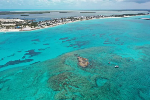 Aerial view of boats anchored off coral rocks with North Bimini in background.