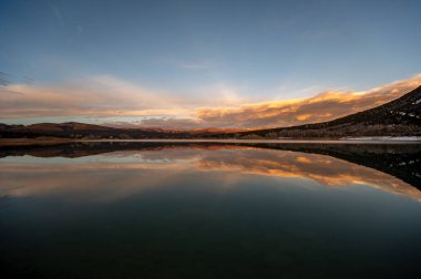 Harvey Gap State Park, Colorado 'daki Grass Valley Rezervuarı üzerindeki renkli günbatımı bulutu göllere yansıyor..