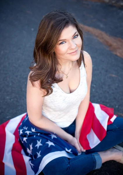 Junge glückliche Patriotin sitzt mit dem Amerikaner auf dem Boden — Stockfoto