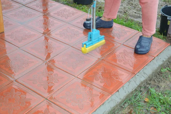 Woman washes floor tiles with a mop with a water