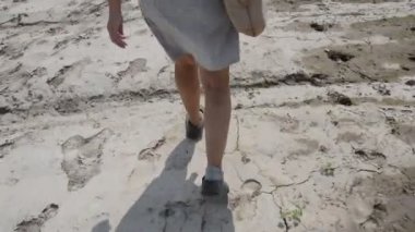 Bir kadın ıssız bir kum tarlasında yürüyor.