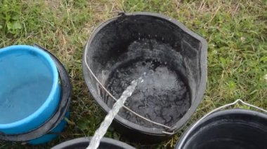 Su bir bahçe hortumundan kovalara dökülür.