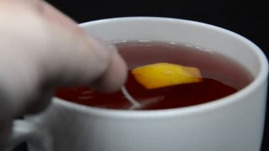 Isıtılmış çay soğur ve siyah arka planda beyaz bir fincanda karıştırılır.