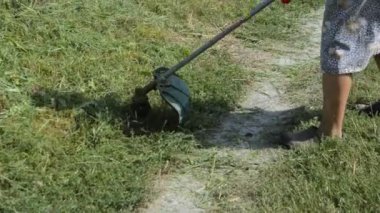 Kadın el budama makinesiyle çim biçiyor.