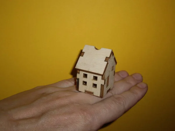 Mały Drewniany Domek Dłoni Mężczyzny Żółtym Tle — Zdjęcie stockowe
