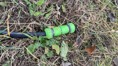 Sebze bahçesini sulamak için kullanılan plastik ve metal bahçe hortumu.