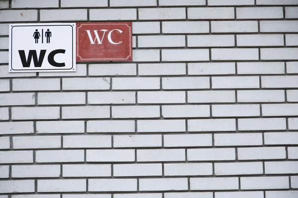 Toilet bord voor man en vrouw op witte bakstenen muur — Stockfoto