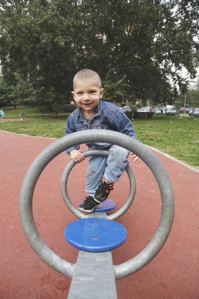 Happy child boy playing seesawing in playground at park — Stock Photo, Image