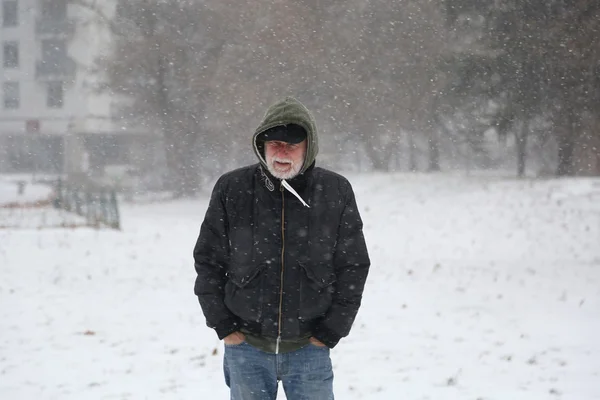 Hombre mayor de cincuenta años en tormenta de nieve afuera en el parque — Foto de Stock