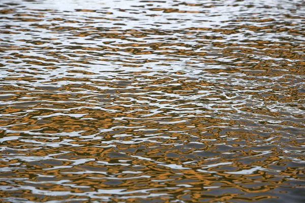 Orange blau-weiße Reflexion auf Oberflächenwasser mit Wellen — Stockfoto