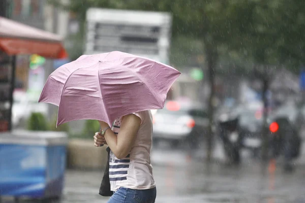Donna che cammina con gli ombrelli nella città piovosa — Foto Stock