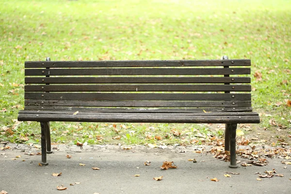 Vecchia panchina del parco sul sentiero vicino all'erba verde in autunno — Foto Stock