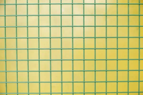 Green Protective metallic grid on yellow background — Stock Photo, Image