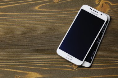 Beyaz Samsung Galaxy S6 ve kenar vuruşta ahşap masa