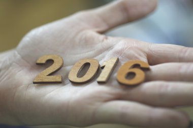Yeni yıl 2016 ahşap numaraları bir elinde tutan kadın
