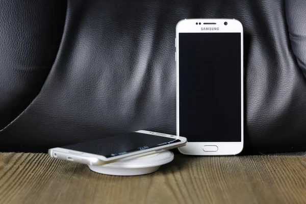 Ahşap masa üzerinde kablosuz şarj cihazı ile beyaz Samsung Galaxy S6 ve kenar atış