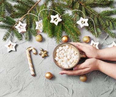 Marşmelovlu Noel kahvesi. Kadın elleri arka plandaki Noel ağacında bardak tutuyor. Mutlu noeller ve yeni yıl düzüşmeleri. Kış kutlamaları, tatiller ve hafta sonları. Noel yemeği.
