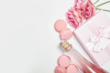 Makarna tatlısı ve bir şişe şampanya. Romantik kahvaltı ve akşam yemeği Sevgililer Günü tebrik kartı. Çiçekler ve hediye kutuları beyaz arka planda. Mutlu yıllar ve anneler günü şablonu