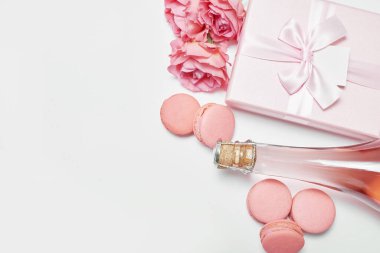 Makarna tatlısı ve bir şişe şampanya. Romantik kahvaltı ve akşam yemeği Sevgililer Günü tebrik kartı. Çiçekler ve hediye kutuları beyaz arka planda. Mutlu yıllar ve anneler günü şablonu