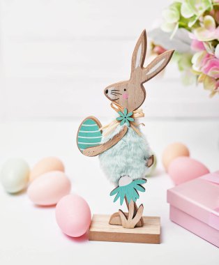 Mutlu Paskalya yumurtaları ve tavşan tebrik kartı. Çiçek buketi ve beyaz arka planda hediye kutusu