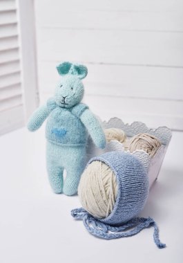 Dikiş ve örgü. Hobiler ve yaratıcılık. Çocuklar için örgü. Örgü oyuncaklar, tavşan ve şapka. El yapımı oyuncak tavşan. Bebek şapkası. İplik, iplik ve toplar.