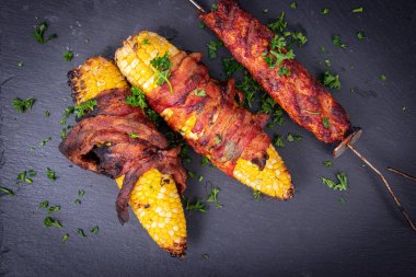 Domuz pastırmasına sarılı mısır ve kebap.