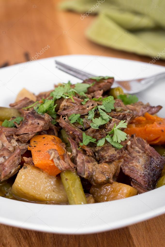 Braised beef pot roast stew with vegetables on table