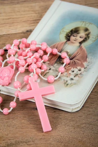 Rosario rosado sobre un libro religioso en la mesa — Foto de Stock