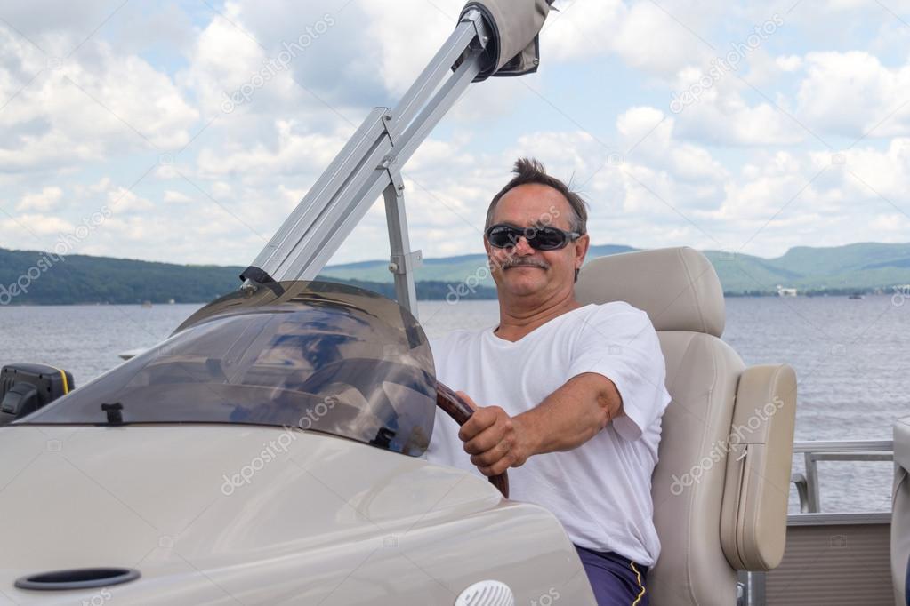 mature men driving a pontoon boat on a lake