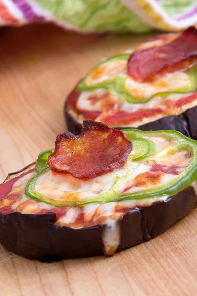 Pizza su fette di melanzana alla griglia sul tavolo — Foto Stock